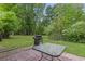 Backyard patio with a barbecue grill and glass table surrounded by lush greenery at 86 Beaver Pond Loop # 33, Pawleys Island, SC 29585