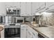 Functional kitchen featuring modern stainless steel appliances, white cabinets, and open view into the living room at 86 Beaver Pond Loop # 33, Pawleys Island, SC 29585