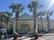 Charming clubhouse featuring a welcoming entrance framed by vibrant palm trees on a sunny day at 1000 Ray Costin Way # 114, Murrells Inlet, SC 29576