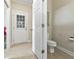 Bright bathroom featuring a toilet, beige tile flooring, and a white door leading to the outside at 127 Willow Bay Dr., Murrells Inlet, SC 29576
