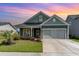 Charming single-story home featuring a manicured lawn, gray siding, a black metal roof, and an attached two-car garage at 1827 Parish Way, Myrtle Beach, SC 29577