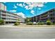 View of the condo complex exterior with parking lot, mature landscaping, and multiple floors with balconies at 210 N Ocean Blvd. # 234, North Myrtle Beach, SC 29582