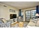 Comfortable living room featuring stylish furnishings, a large TV, access to balcony, and wood grain flooring at 210 N Ocean Blvd. # 234, North Myrtle Beach, SC 29582