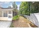 Backyard features a white picket fence surrounding a grassy area, accessible from the screened porch and paver patio at 2405 Brick Dr., Longs, SC 29568