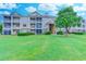 Three-story condo building featuring screened porches and a lush green lawn and mature landscaping at 290 Woodlands Way Nw # 10, Calabash, SC 28467