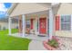 Close-up of the charming front porch with a bench, red door with decorative detail, and flower garden at 409 Hunley Ln., Myrtle Beach, SC 29577