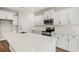 Stylish kitchen with white cabinets, stainless steel appliances, island with quartz countertop, and modern faucet at 605 Carter Reid Ct., Longs, SC 29568