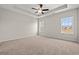 Spacious bedroom featuring tray ceilings, neutral walls, soft carpet, and natural light from two windows at 609 Carter Reid Ct., Longs, SC 29568