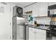Compact kitchen with white cabinets, modern stainless-steel appliances, and overhead washer/dryer at 6900 N Ocean Blvd. # 208, Myrtle Beach, SC 29572