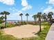 Empty volleyball court at the beach with beautiful palm trees, greenery, and blue skies with clouds in the background at 7100 Ocean Blvd. N # 1425, Myrtle Beach, SC 29572