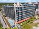 Exterior shot of a high-rise hotel, a pool, parking lot and greenery, and blue skies with fluffy white clouds at 7100 Ocean Blvd. N # 1425, Myrtle Beach, SC 29572