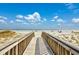 Scenic boardwalk leading to a beautiful sandy beach with clear blue skies above at 7509 N Ocean Blvd. # 101, Myrtle Beach, SC 29572