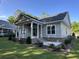 Charming exterior elevation with a covered porch, gray siding, and brick accents surrounded by a lush lawn at 924 Morrall Dr., North Myrtle Beach, SC 29582