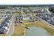 Aerial view showcasing a community with a pool, tennis courts, and well-manicured green spaces by a lake at 1031 Cascade Loop, Little River, SC 29566