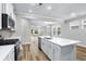 Well-lit kitchen showcasing white cabinets, stainless steel appliances, a large island with a sink, and open access to living spaces at 1031 Cascade Loop, Little River, SC 29566