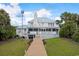 Back exterior view of coastal home featuring a spacious porch, green yard, and lush tropical landscaping at 109 Pioneer Loop, Georgetown, SC 29440