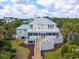 Back exterior view of coastal home featuring a spacious deck, green yard, and lush tropical landscaping at 109 Pioneer Loop, Georgetown, SC 29440