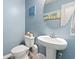 Powder room featuring a pedestal sink, commode, and beach-themed artwork against blue walls at 109 Winding Path Dr., Loris, SC 29569