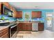 Well-lit kitchen features stainless steel appliances, wood cabinets and blue accent wall at 109 Winding Path Dr., Loris, SC 29569