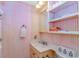 Small bathroom with a charming vanity, open shelves and pink striped wallpaper at 1100 Possum Trot Rd. # H136, North Myrtle Beach, SC 29582