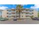 Attractive multi-story condo building with large balconies and lush palm tree in front at 1100 Possum Trot Rd. # H136, North Myrtle Beach, SC 29582