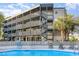 Community pool surrounded by building featuring outdoor staircase and walkways and some lounge seating at 1500 Cenith Dr. # F103, North Myrtle Beach, SC 29582