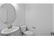Clean half bathroom with a pedestal sink, toilet, and round mirror at 1611B S Ocean Blvd., Surfside Beach, SC 29575