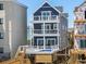 Stunning three-story home with a blue exterior, complemented by multi-level balconies with ocean views at 1611B S Ocean Blvd., Surfside Beach, SC 29575