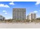 Exterior view of the building from the beach showcasing multiple floors of balconies and palm trees lining the sand at 2300 N Ocean Blvd. # 1430, Myrtle Beach, SC 29577