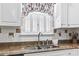 Close-up of stainless steel kitchen sink set in brown granite countertops, complemented by white cabinets and natural light at 255 Tibton Circle, Myrtle Beach, SC 29588