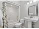 Bright bathroom featuring a shower-tub combo, a decorative mirror, and a white pedestal sink at 3157 Hermitage Dr., Little River, SC 29566