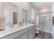 Well-lit bathroom with double sinks, large mirrors, shower and gray cabinets at 384 Rookroost Circle, Conway, SC 29526