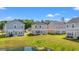 Spacious backyard view of several two-story homes in a neighborhood with well-maintained lawns and a pond at 3968 Hibiscus Dr., Little River, SC 29566