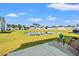 A concrete patio area that extends into a large lawn with pond, blue sky, and neighborhood homes in the background at 3968 Hibiscus Dr., Little River, SC 29566