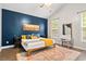 Cozy bedroom with a navy accent wall, a comfortable bed, wood floors, and bright natural light from the window at 4697 Farm Lake Dr., Myrtle Beach, SC 29579
