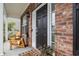 Inviting front porch featuring a black front door, brick accents, and two wooden chairs at 4697 Farm Lake Dr., Myrtle Beach, SC 29579
