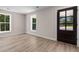 Bright living room with wood-look flooring, two large windows and a dark-stained wood door at 509 S Rosemary Ave., Andrews, SC 29510