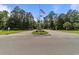 Community entrance featuring an American flag, security booth, and landscaped roundabout at 6465 Royal Pine Dr., Myrtle Beach, SC 29588