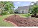 Backyard featuring a manicured lawn, mulch bed with a brick border, mature trees, and patio furniture at 78 Saltwind Loop, Murrells Inlet, SC 29576