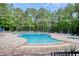 Community pool surrounded by lounge chairs and umbrellas, all enclosed by a tall forest of trees at 78 Saltwind Loop, Murrells Inlet, SC 29576