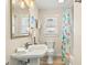 Bathroom with pedestal sink, window, and shower with coral shower curtain at 118 Seaside St., Holden Beach, NC 28462
