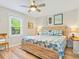 Bright bedroom with a wooden bed frame, ceiling fan, and a window offering natural light at 118 Seaside St., Holden Beach, NC 28462