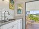 Well-lit kitchen with stainless steel sink, granite countertop and door leading to a wooden deck with seating at 118 Seaside St., Holden Beach, NC 28462