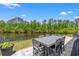 Back patio with outdoor dining table and chairs overlooking a serene pond and lush greenery at 127 Emerald Rush Ct., Longs, SC 29568