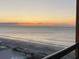 A view of a wide sandy beach meets ocean waves under a yellow and orange sunset at 1501 S Ocean Blvd. # 1107, Myrtle Beach, SC 29577