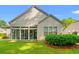 Rear exterior view of house showcasing a sunroom and landscaped yard at 1617 Tradition Club Dr., Pawleys Island, SC 29585