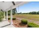 Inviting front porch with white columns, landscaping, and views of an open field, perfect for relaxing outdoors at 1676 Elder Ln., Galivants Ferry, SC 29544