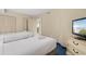 Bright bedroom with two twin beds, a dresser, and a beach view on the TV screen at 2000 N Ocean Blvd. # 301, Myrtle Beach, SC 29577