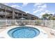 Outdoor hot tub surrounded by white fencing, condos and sunbathing chairs, perfect for relaxation at 206 Maison Dr. # Q-204, Myrtle Beach, SC 29572