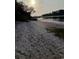 A quiet beach scene featuring a calm river, vegetation, and a distant dock silhouetted by the setting sun at 2128 Adams Circle, Little River, SC 29566